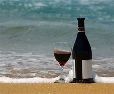 Bottle and glass of wine on the beach.